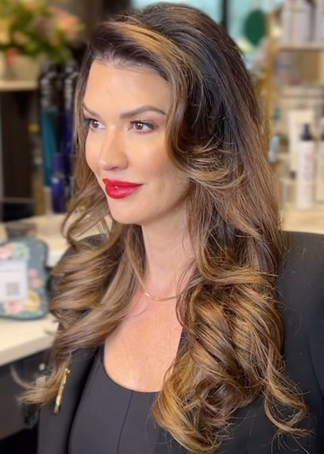 Woman with long, wavy hair and red lipstick in a salon.