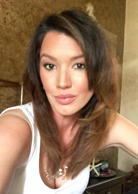 Woman with long brown hair taking a selfie indoors.