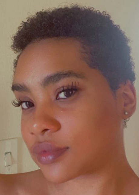 Woman with short curly hair and natural makeup looking into the camera.