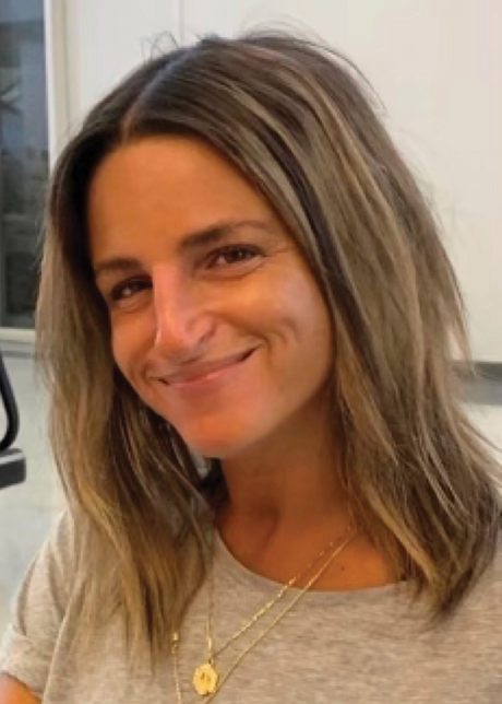 A woman with shoulder-length hair and a gray shirt smiling at the camera.