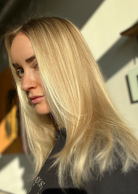 Woman with long, blonde hair looking at the camera in sunlight.