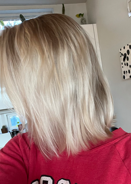 Person with shoulder-length, blonde hair wearing a red shirt in a home setting.
